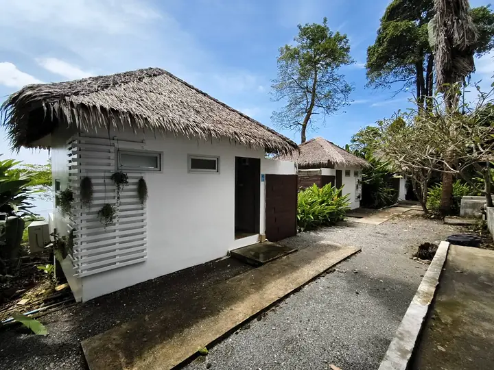 Een witte Front Sea View-bungalow met een rieten dak aan het pad door de tuin