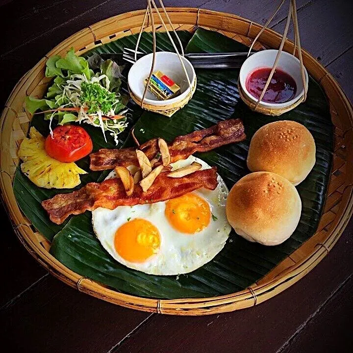 Breakfast with eggs, bacon, salad and bread rolls