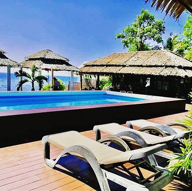 Sun loungers by the pool with the sea beyond