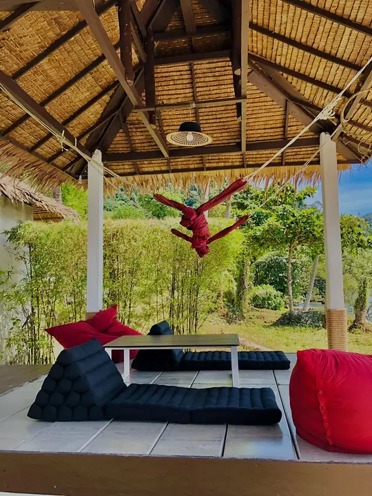 Cabana with floor cushions, red beanbags and a hammock in the garden