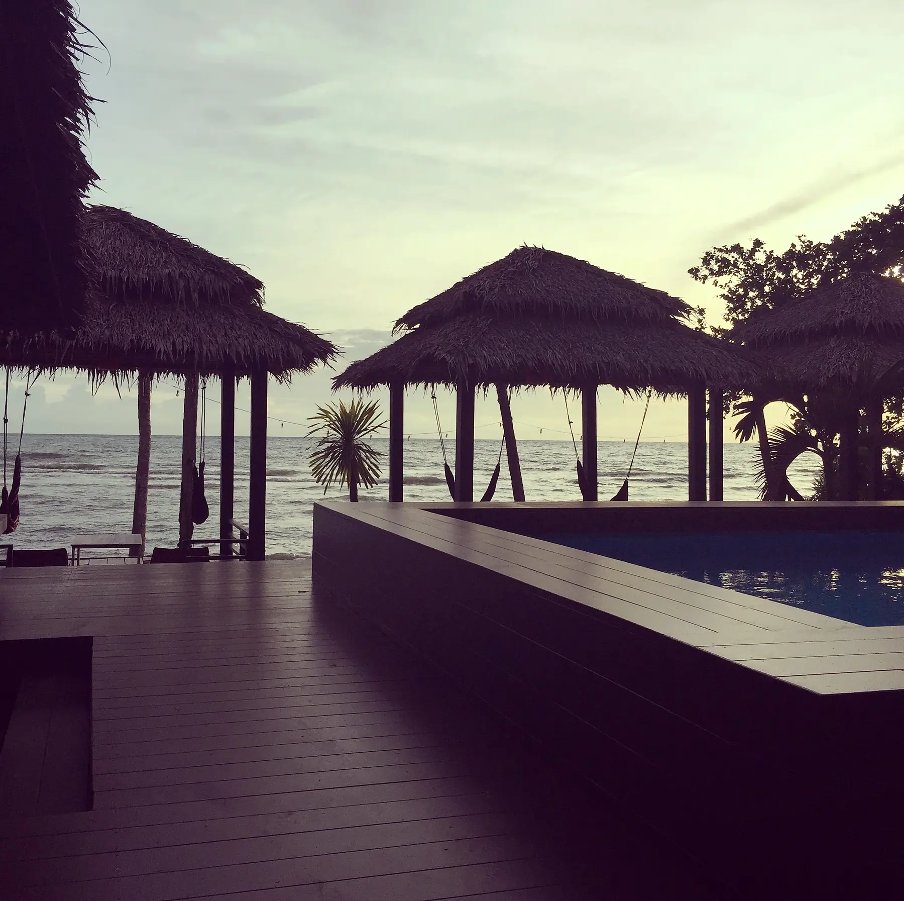 Thatched cabanas and the pool at dusk
